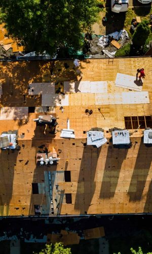 A worker replace shingles on the roof of a home repairing the roof of a home